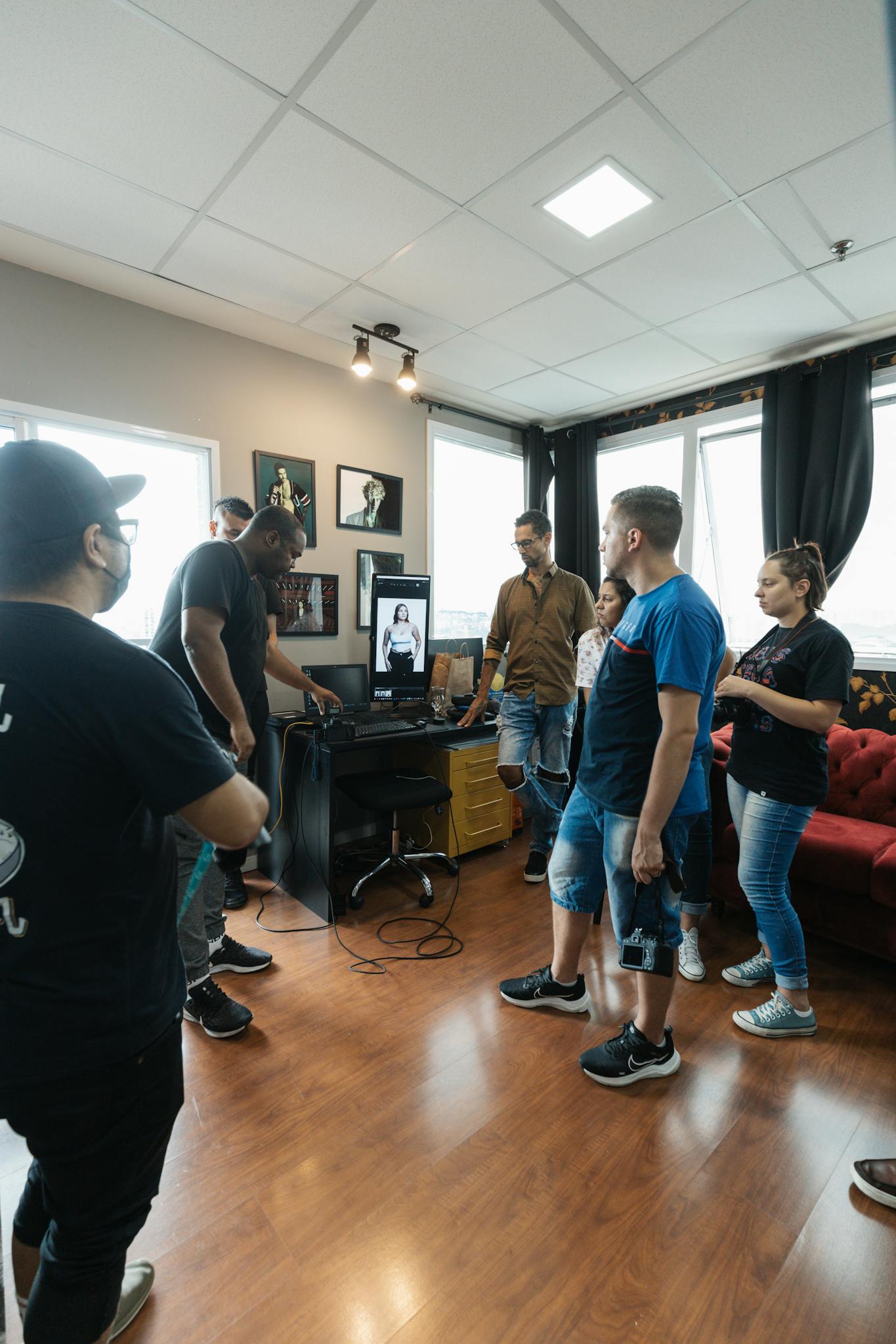 Group of people gathered around a computer discussing video editing in a modern studio setting.